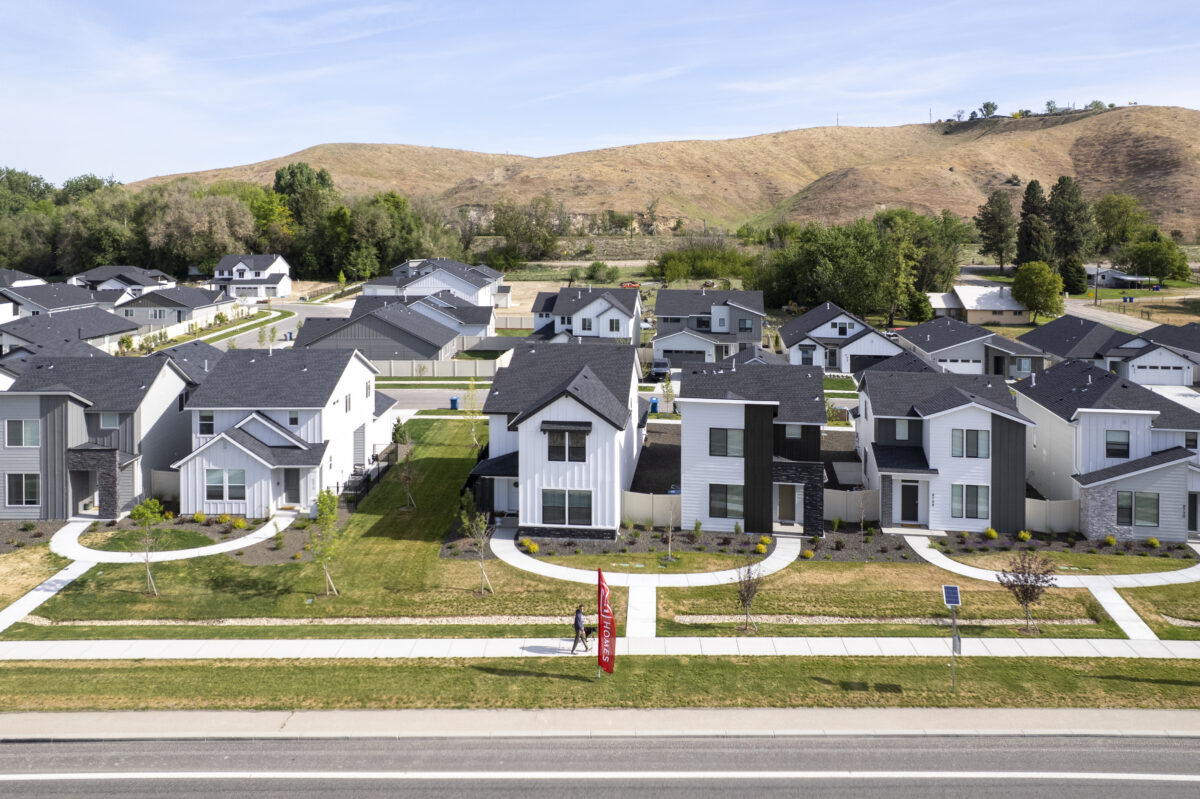 Ground-level aerial image highlighting a row of stylish new CBH Homes with front porches, large windows, and curved walkways leading to the sidewalk, against a hillside backdrop.