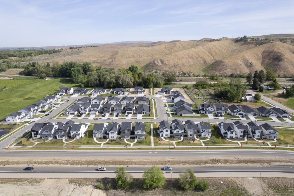 Straight-on aerial shot of a completed CBH Homes subdivision showing the symmetry of the homes, central streets, and the hilly terrain surrounding the development.