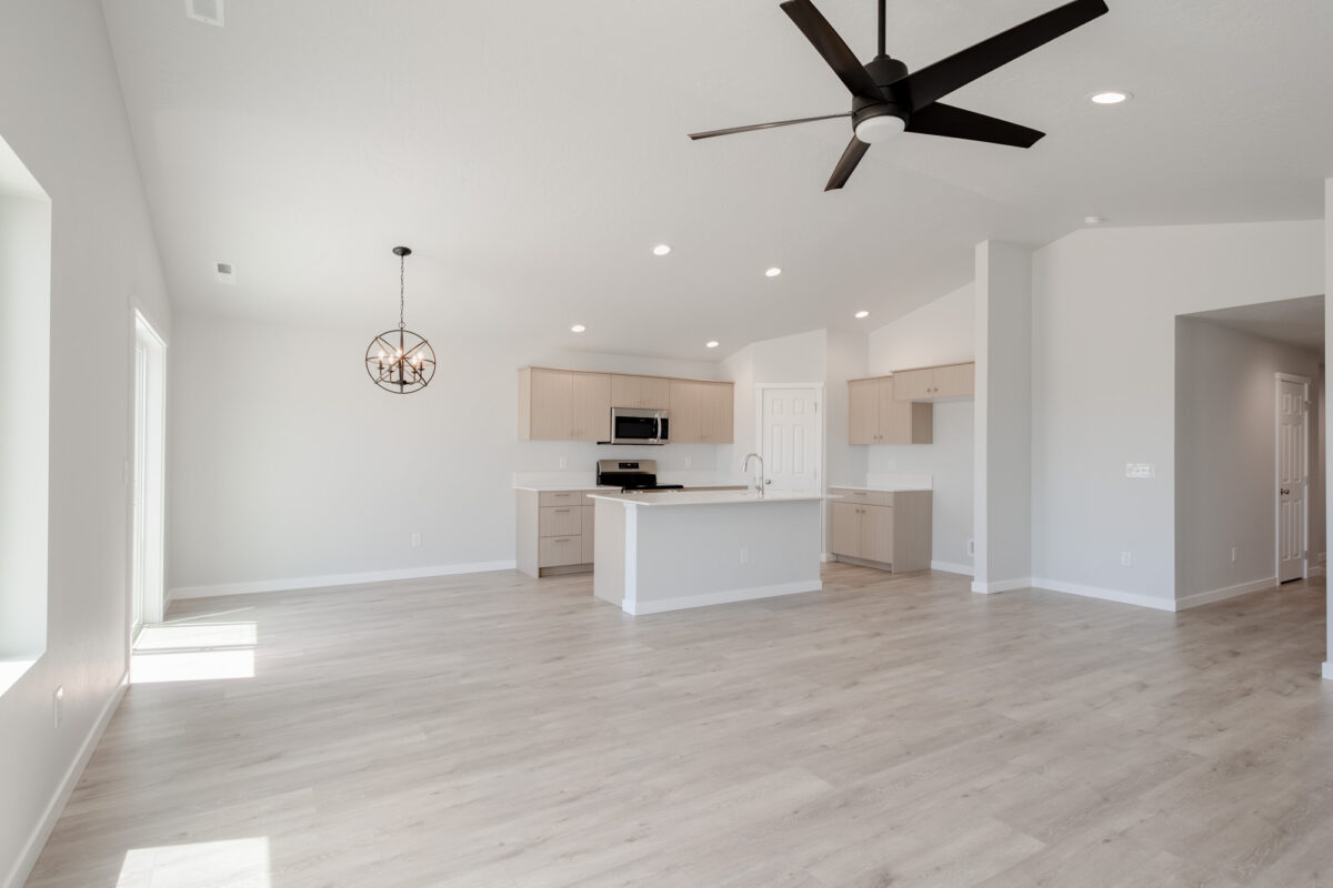 Open-concept kitchen and living room in a new Bennett floor plan home at Topaz Ranch West, featuring vaulted ceilings and light wood finishes.