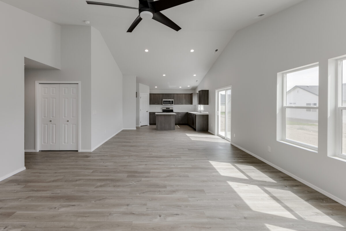 Contemporary kitchen design with dark espresso-toned cabinets, matching matte black faucet and hardware, and sleek gray countertops. Includes a central island, stainless steel appliances, and a clean layout under bright recessed lighting and neutral walls.