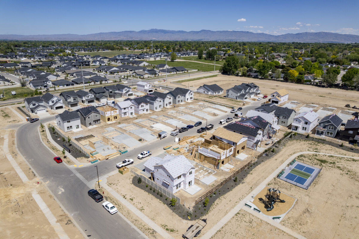 Wide-angle image of a developing CBH Homes neighborhood, featuring foundations, framing work, and proximity to a playground and pickleball courts.