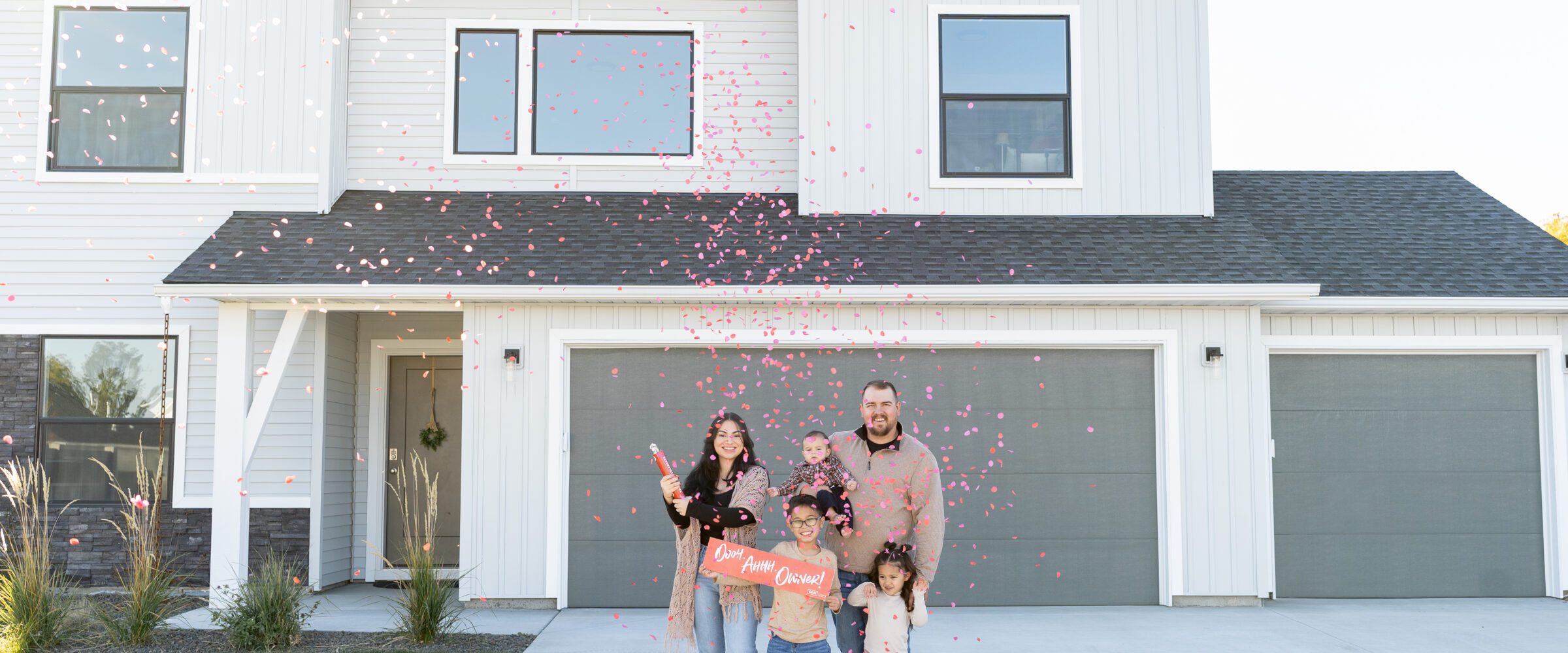 First-time homebuyers celebrating in front of their new CBH home with their family.