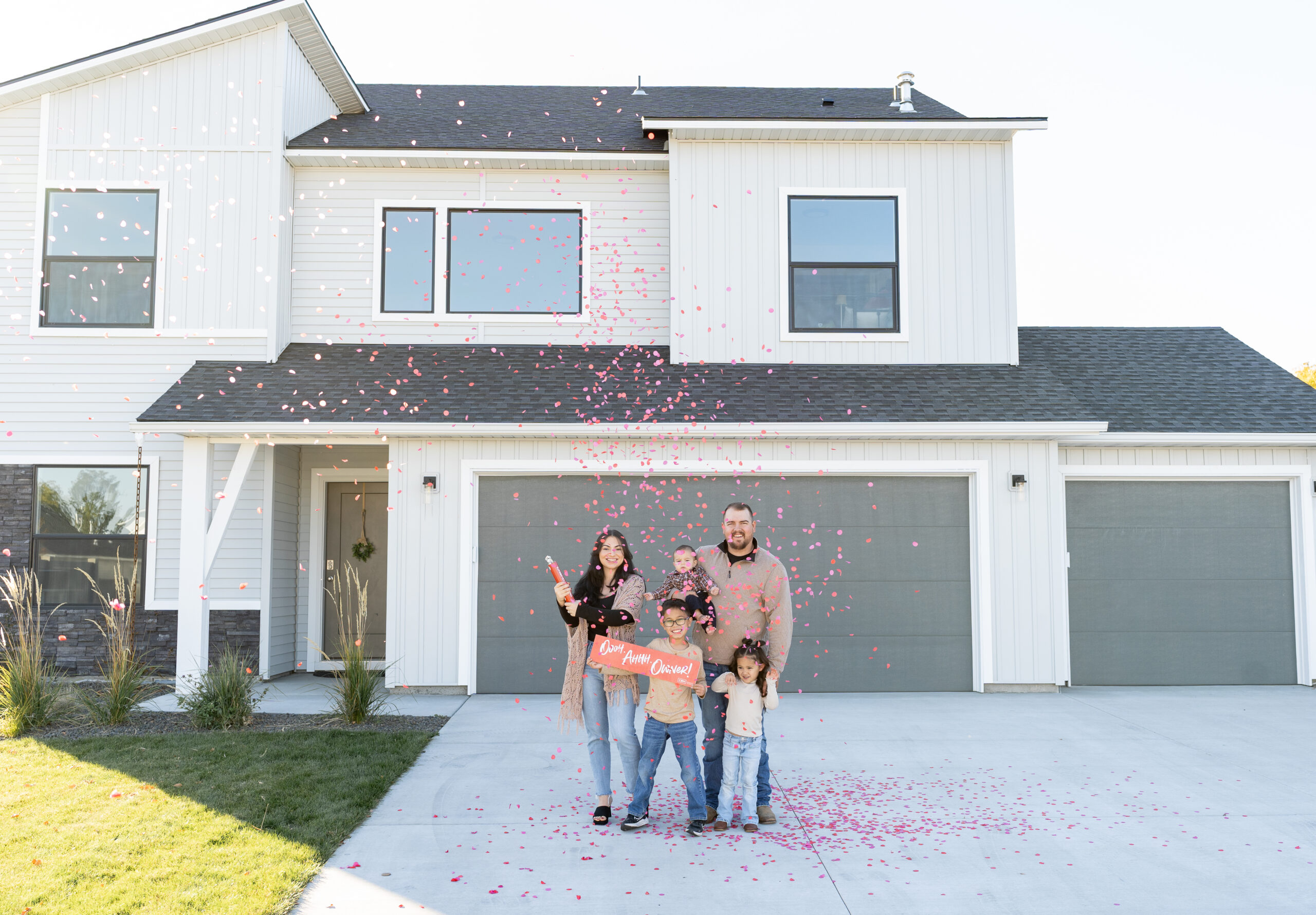 First-time homebuyers celebrating in front of their new CBH home with their family.