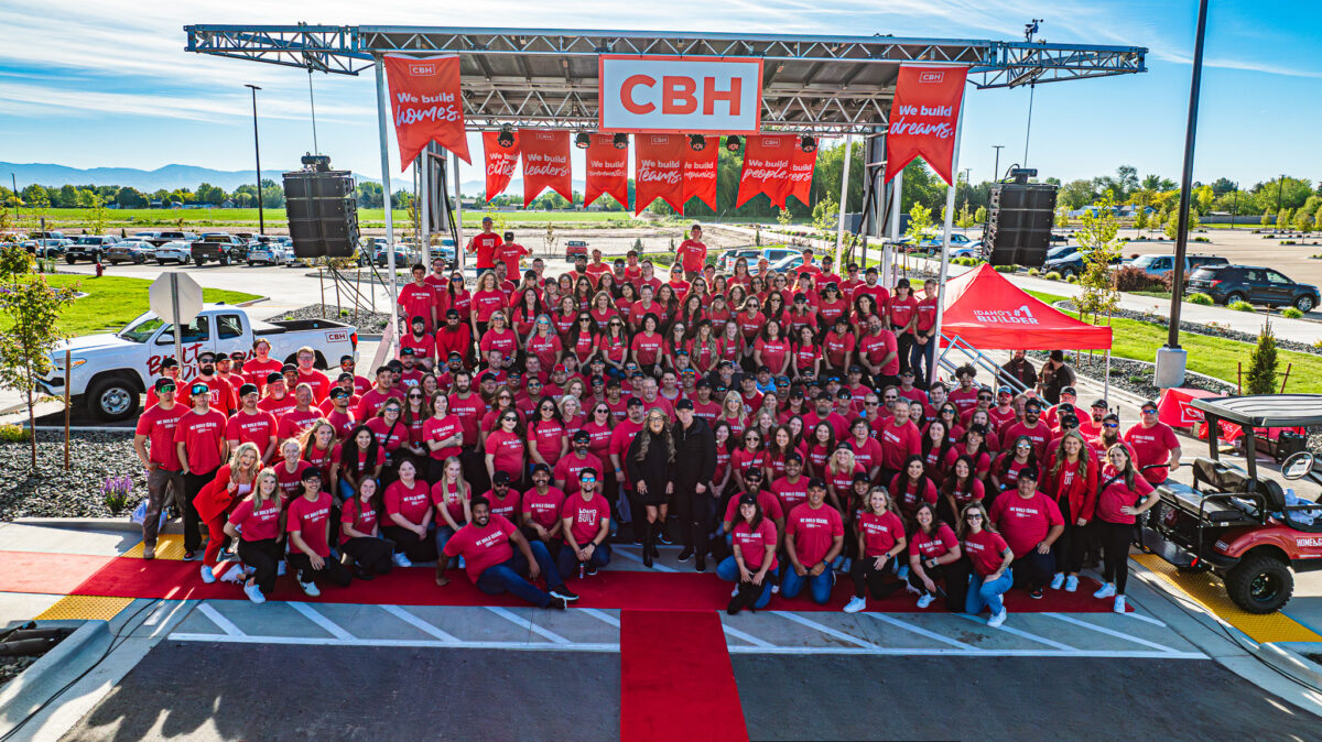 he CBH Homes team gathers for a group photo during a First Quarter Company Kickoff event, celebrating culture, teamwork, and recognition as a Fortune Best Workplace. Team members wear matching red shirts under a branded CBH stage.