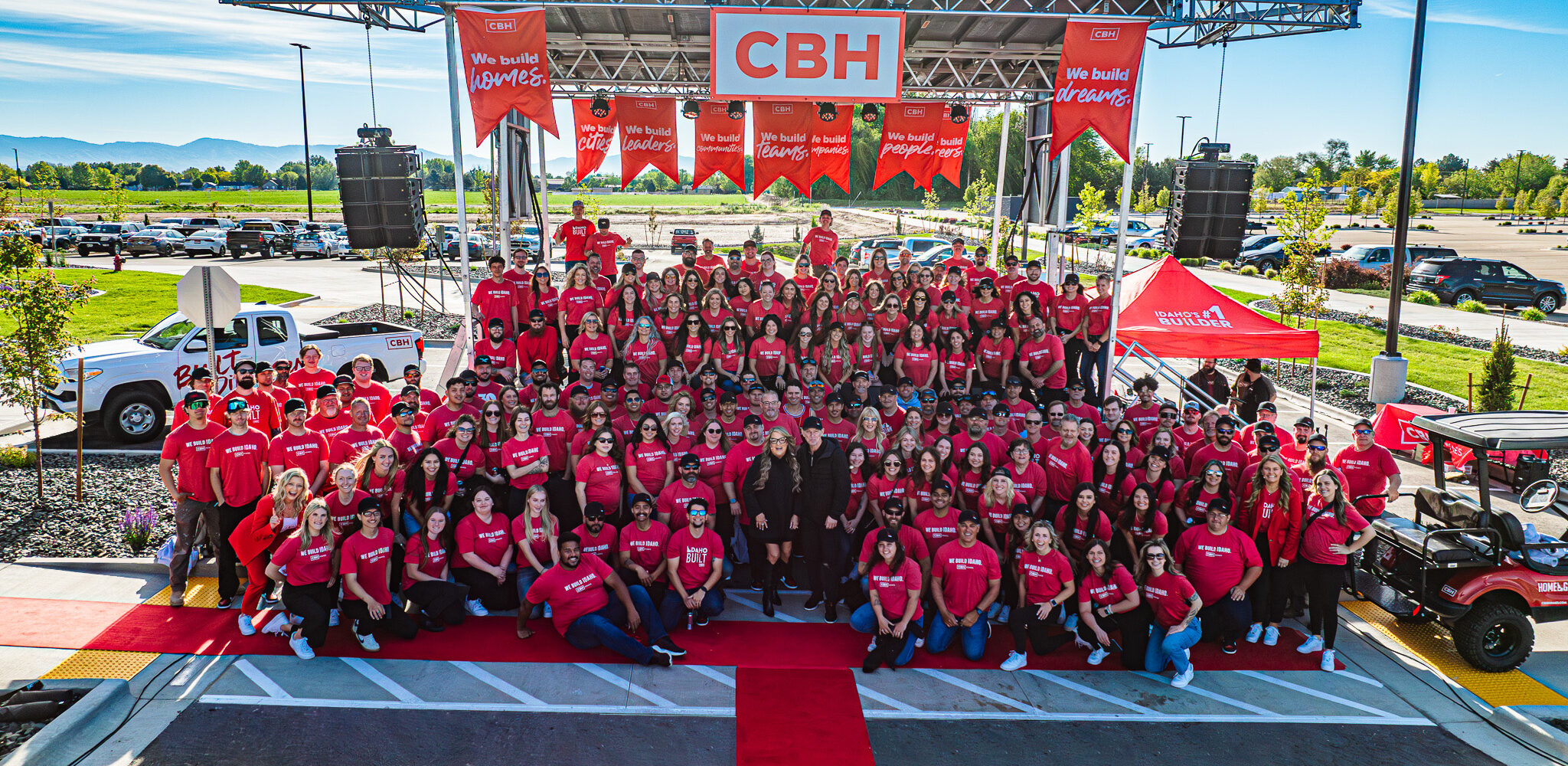 he CBH Homes team gathers for a group photo during a First Quarter Company Kickoff event, celebrating culture, teamwork, and recognition as a Fortune Best Workplace. Team members wear matching red shirts under a branded CBH stage.