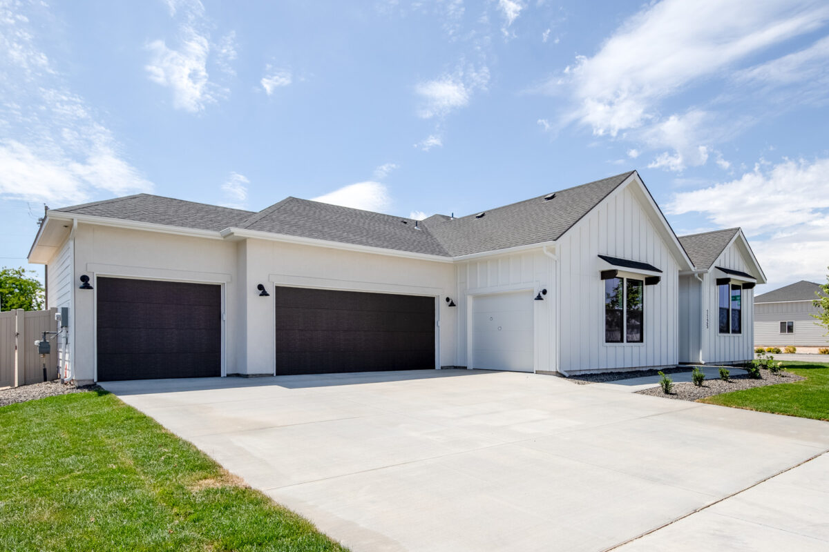 Exterior view of the CBH Homes Riverbirch 2626 floor plan featuring a three-car garage, modern white siding, and gabled roof design.