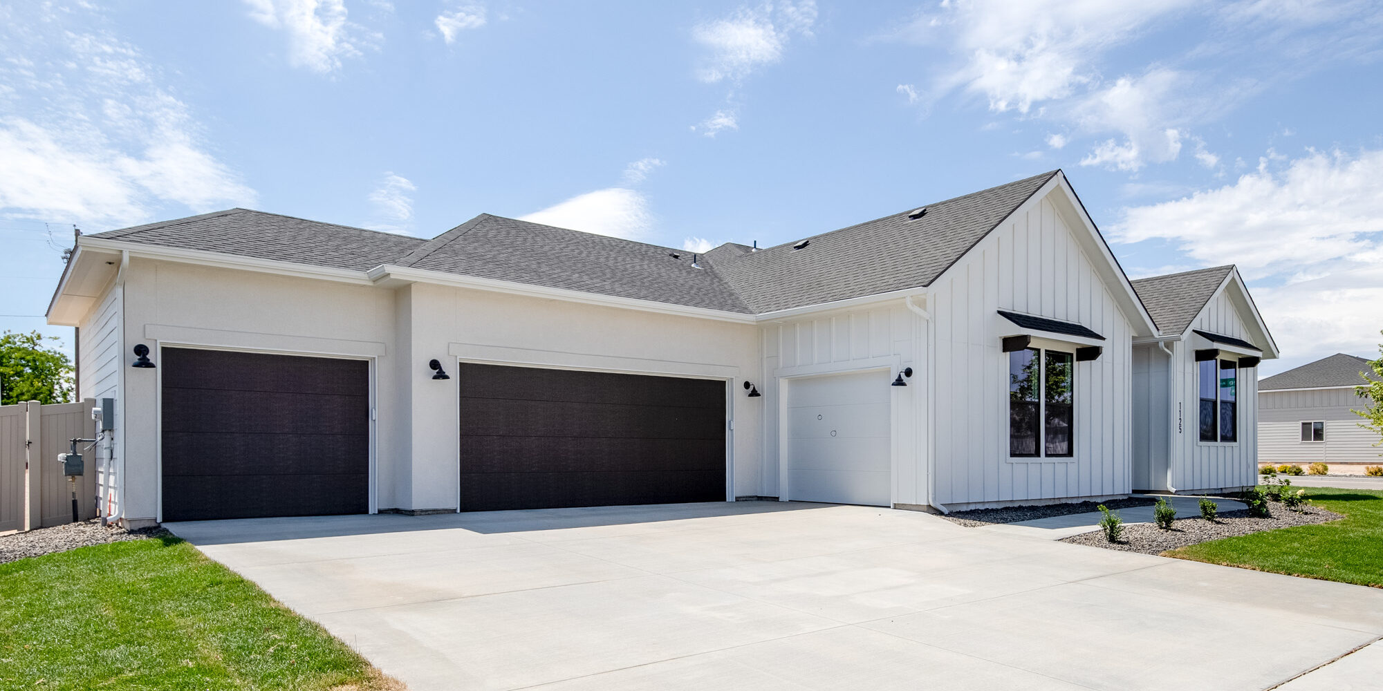Exterior view of the CBH Homes Riverbirch 2626 floor plan featuring a three-car garage, modern white siding, and gabled roof design.