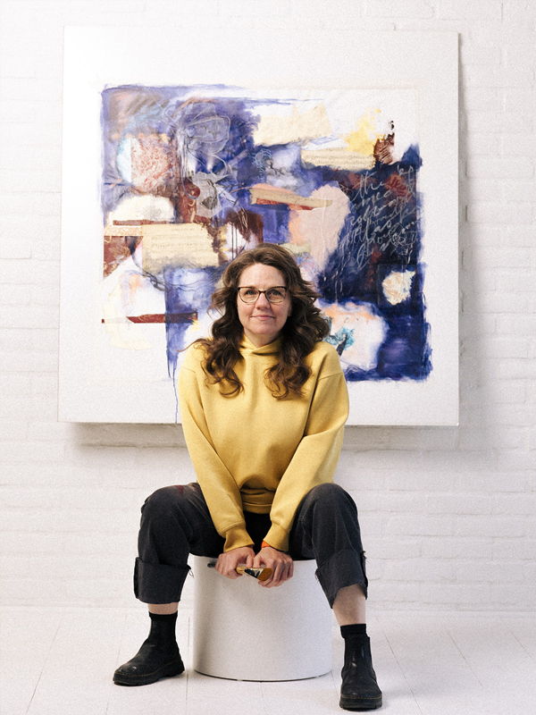 Artist Jodi Miller sitting in front of blue and white painting
