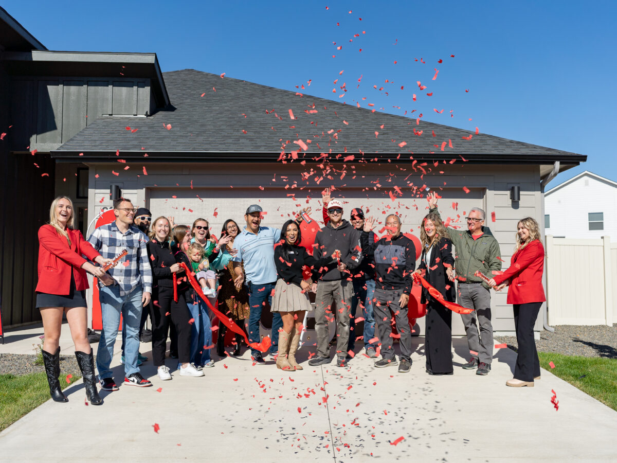 CBH Homes team and homeowners celebrating a ribbon-cutting ceremony at the grand opening of a new community with confetti in front of a new home.