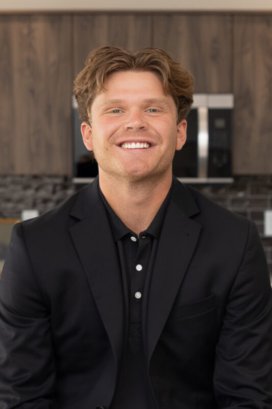 Professional headshot of Cash Cowdery, CBH Homes sales professional, smiling in a modern model home.